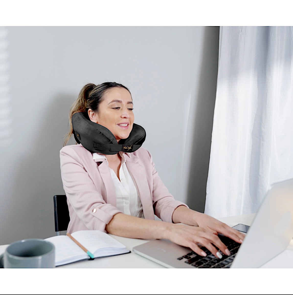 person wearing pillow for neck and back pain while working - black
