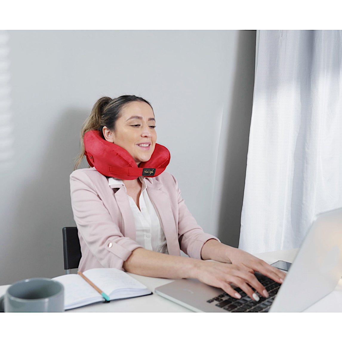 person wearing pillow for neck and back pain while working - red