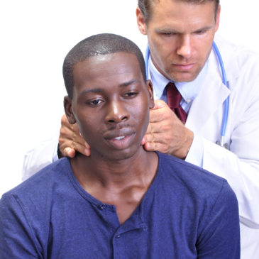 Young man receives medical examination by doctor who feels the neck checking for enlarged lymph nodes