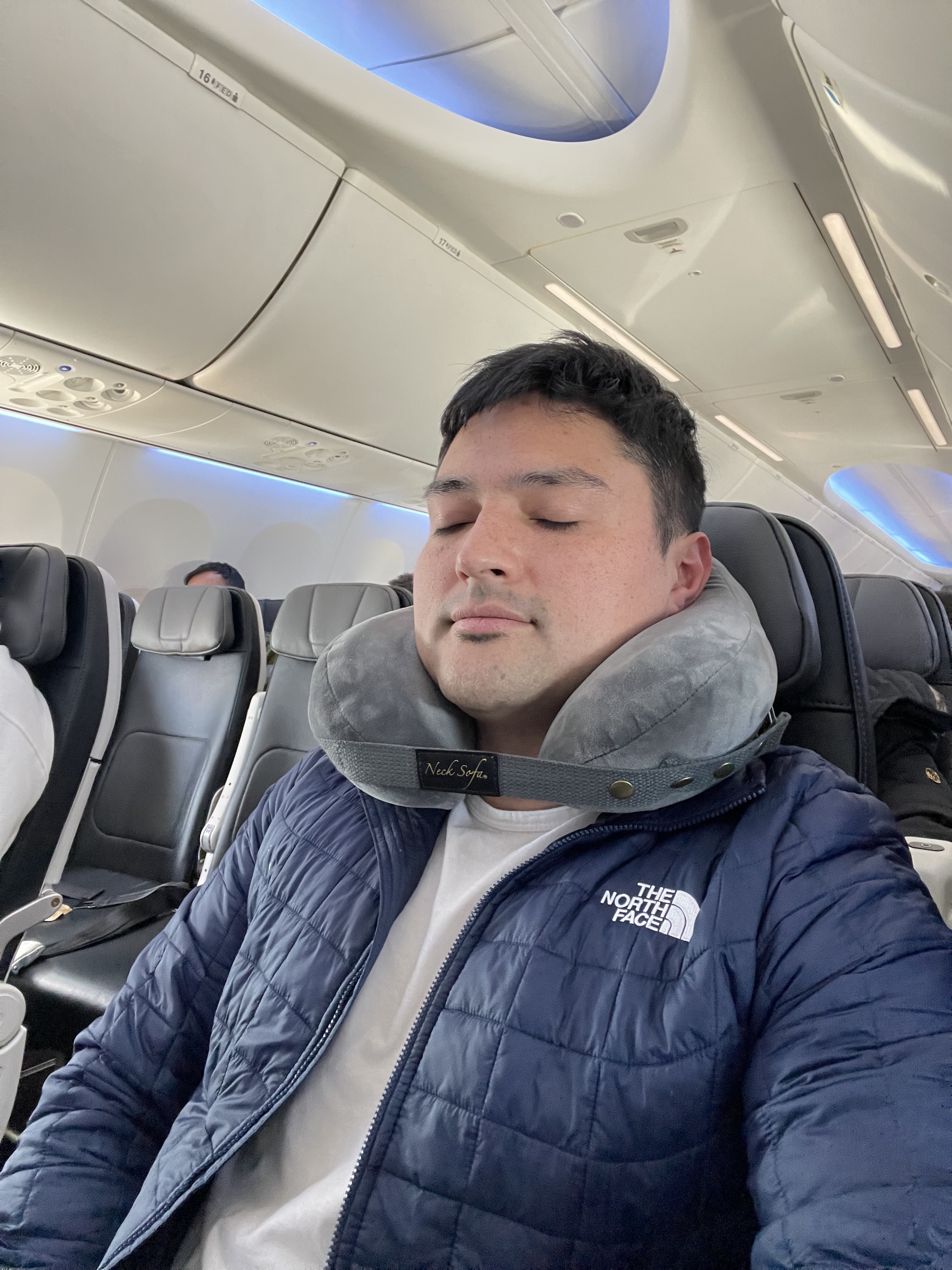 Traveler using Neck Sofa® pillow for neck support on airplane”