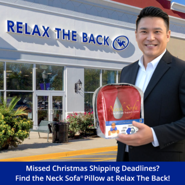Picture of an Asian man standing in front of a Relax The Back Store holding a Burgundy Neck Sofa® Pillow