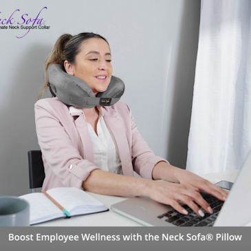 A woman at the office wearing a Grey Neck Sofa Pillow working on the computer related.